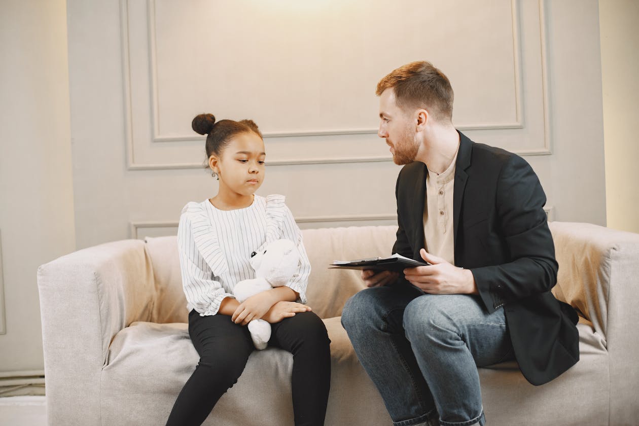 Bambina in seduta con psicologo infantile in stanza accogliente | psicologo per bambini