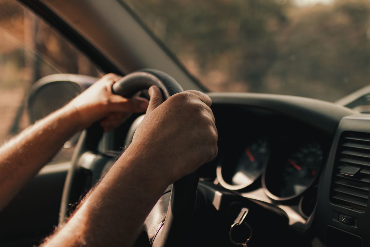 Mani sul volante in una scena di guida quotidiana, senza elementi di pericolo